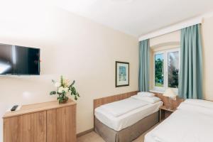 a hotel room with two beds and a flat screen tv at Inselhotel Faakersee in Faak am See