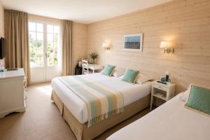 a hotel room with two beds and a window at Hôtel Villa Flornoy Pornichet Baie de la Baule in Pornichet