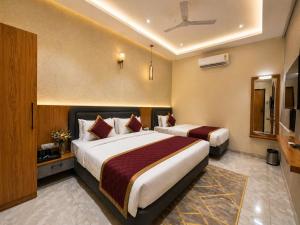 a hotel room with two beds and a television at Travinities Premier, Ujjain in Ujjain +17 photos