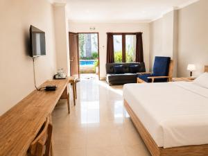 a bedroom with a bed and a couch and a television at Radha Bali Hotel in Kuta