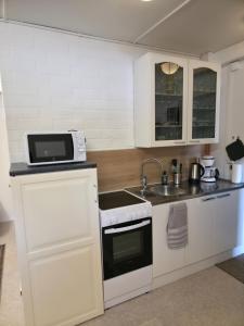 a white kitchen with a sink and a microwave at Kotoisa 2 in Seinäjoki