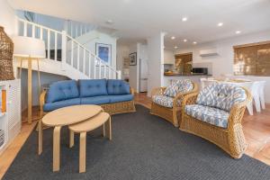 a living room with a blue couch and chairs and a table at Sandpiper 21 in Smiths Lake