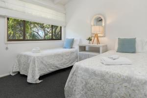 two beds in a white room with a window at Sandpiper 21 in Smiths Lake