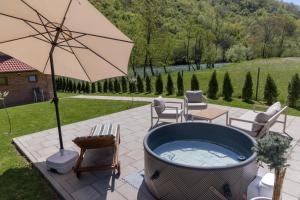 a hot tub with an umbrella on a patio at Villa Alba Rekavice Krupa na Vrbasu in Banja Luka
