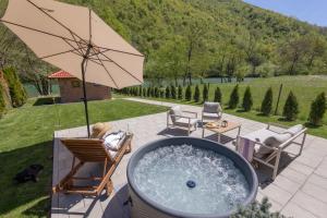 a hot tub with chairs and an umbrella on a patio at Villa Alba Rekavice Krupa na Vrbasu in Banja Luka +32 photos