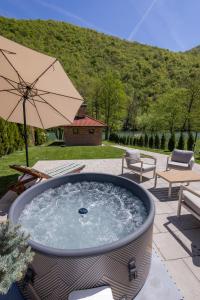 a hot tub with an umbrella on a patio at Villa Alba Rekavice Krupa na Vrbasu in Banja Luka