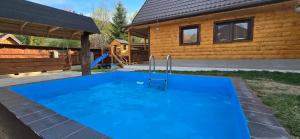 a large blue swimming pool in front of a house at Farma pod Skalkou in Heľpa