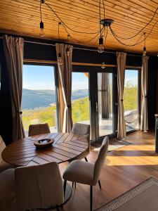 a dining room with a table and chairs and large windows at Pitoresc Cabin in Tranisu