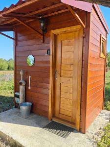 a wooden outhouse with a door in a field at Duva jurta in Bistrica