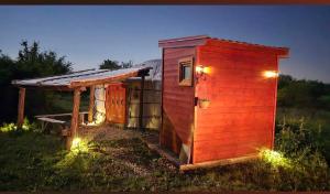 a small red shed with lights in the grass at Duva jurta in Bistrica