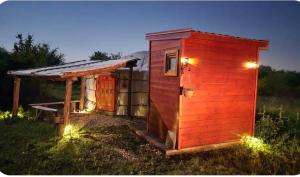 a small red shed with lights in the grass at Duva jurta in Bistrica