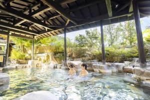 two people in a swimming pool at a resort at Ooedo Onsen Monogatari Terunoyu in Maniwa