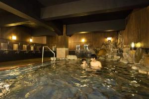 a man and a child in a hot tub at Ooedo Onsen Monogatari Terunoyu in Maniwa