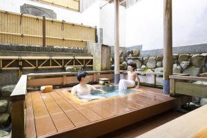 two people sitting in a bath tub in a room at Ooedo Onsen Monogatari Terunoyu in Maniwa +36 photos