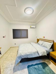 a bedroom with a large bed with a blue rug at Egel Appartement in Yaoundé