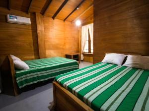 two beds in a room with wooden walls at Vercour Tree House Cabana Sigiriya in Sigiriya