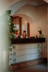 a woman sitting at a counter in front of a mirror at Inselhotel Faakersee in Faak am See