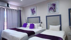 two beds in a hotel room with purple pillows at Zungu b&b in KwaDukuza