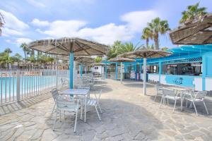 a beach with tables and chairs and umbrellas at Oasis Duna _ Casa Mate Pool in Corralejo