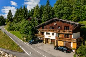 a house with two cars parked in front of a road at Chalet Sandy in Les Gets