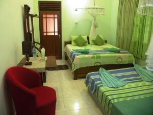 a hotel room with two beds and a chair and a chair at Henderson Airport Residence in Negombo