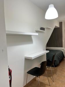 a room with two chairs and a white wall with shelves at Estudio bajo la escalera in Redondela