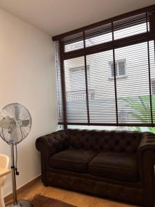 a living room with a brown couch and a fan at Estudio bajo la escalera in Redondela