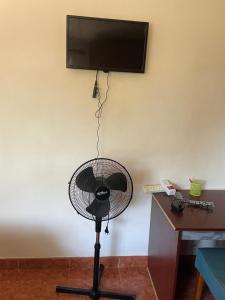 a fan in a room with a television on a wall at Suzie's Nest in Lilongwe