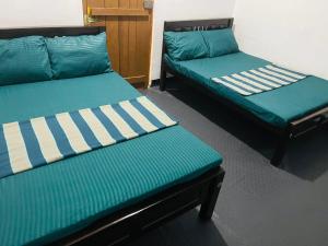 two beds in a room with green and white at NR New Guest in Nilaveli