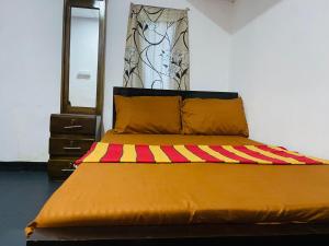 a bed with a yellow and red blanket and a mirror at NR New Guest in Nilaveli
