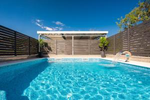 a swimming pool with a water fountain in front of a fence at Villa Ante - Private Pool, Wellness & Gym in Šestanovac