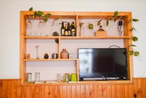 a television on a wooden entertainment center with shelves at La Casa de Doña Adela in Eugenio Bustos