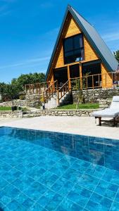 a log cabin with a pool in front of a house at Nora's Chalet in Fshati i Ri
