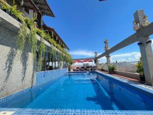 a swimming pool at a resort with a building at Puok Hotel in Phumĭ Puŏk Chăs