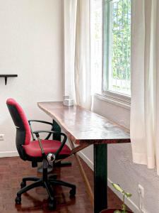 a desk with a red chair next to a window at Di Vine in Maputo