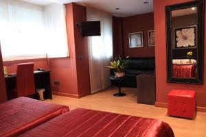 a bedroom with red walls and a couch and a mirror at Hotel Villa de Barajas in Madrid