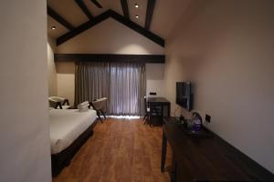 a bedroom with a bed and a desk and a television at Velora The Luxury Resort in Māndu