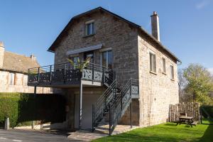 an old brick building with a balcony and a staircase at Gîte de marthe in Sainte-Colombe-de-Peyre