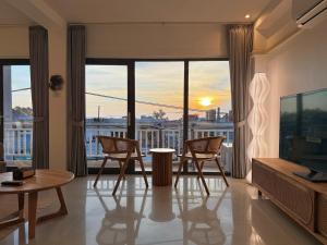a living room with a table and chairs and a large window at Mr Oh in Phuket Karon in Ka Rorn