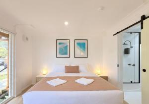 ein weißes Schlafzimmer mit einem großen Bett und zwei Kissen in der Unterkunft Hervey's in Hervey Bay