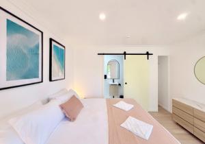 ein weißes Schlafzimmer mit einem großen Bett und einem Spiegel in der Unterkunft Hervey's in Hervey Bay