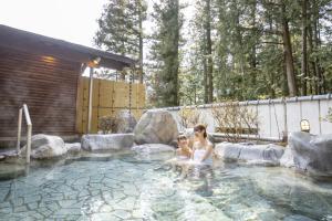 a woman and a child sitting in a swimming pool at Ooedo Onsen Monogatari Gero Bekkan in Gero