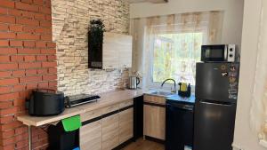 a kitchen with a black refrigerator and a brick wall at Mały cichy zakątek in Ciechocinek