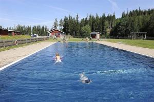 a little girl swimming in a pool of blue water at Vörderåsgården in Transtrand