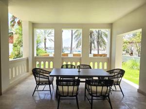 a dining room with a table and chairs and windows at Wateera Jebel Sifah in As Sīfah
