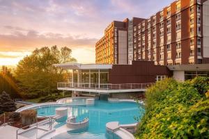 a hotel with a swimming pool in front of a building at Ensana Thermal Aqua in Hévíz