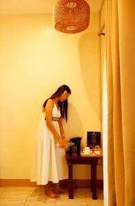 a woman in a white dress standing next to a table at Sunrise Beach Resort in Pooc