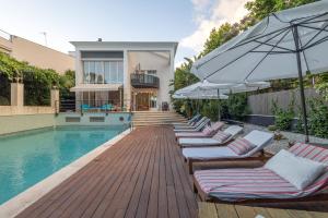 a row of lounge chairs next to a swimming pool at Villa Cela in El Masnou