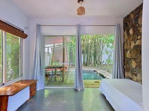 a bedroom with a door open to a swimming pool at Native Lodge et Spa in Mahébourg
