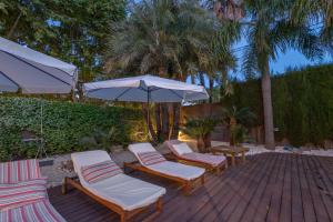 a group of lounge chairs and an umbrella on a patio at Villa Cela in El Masnou
